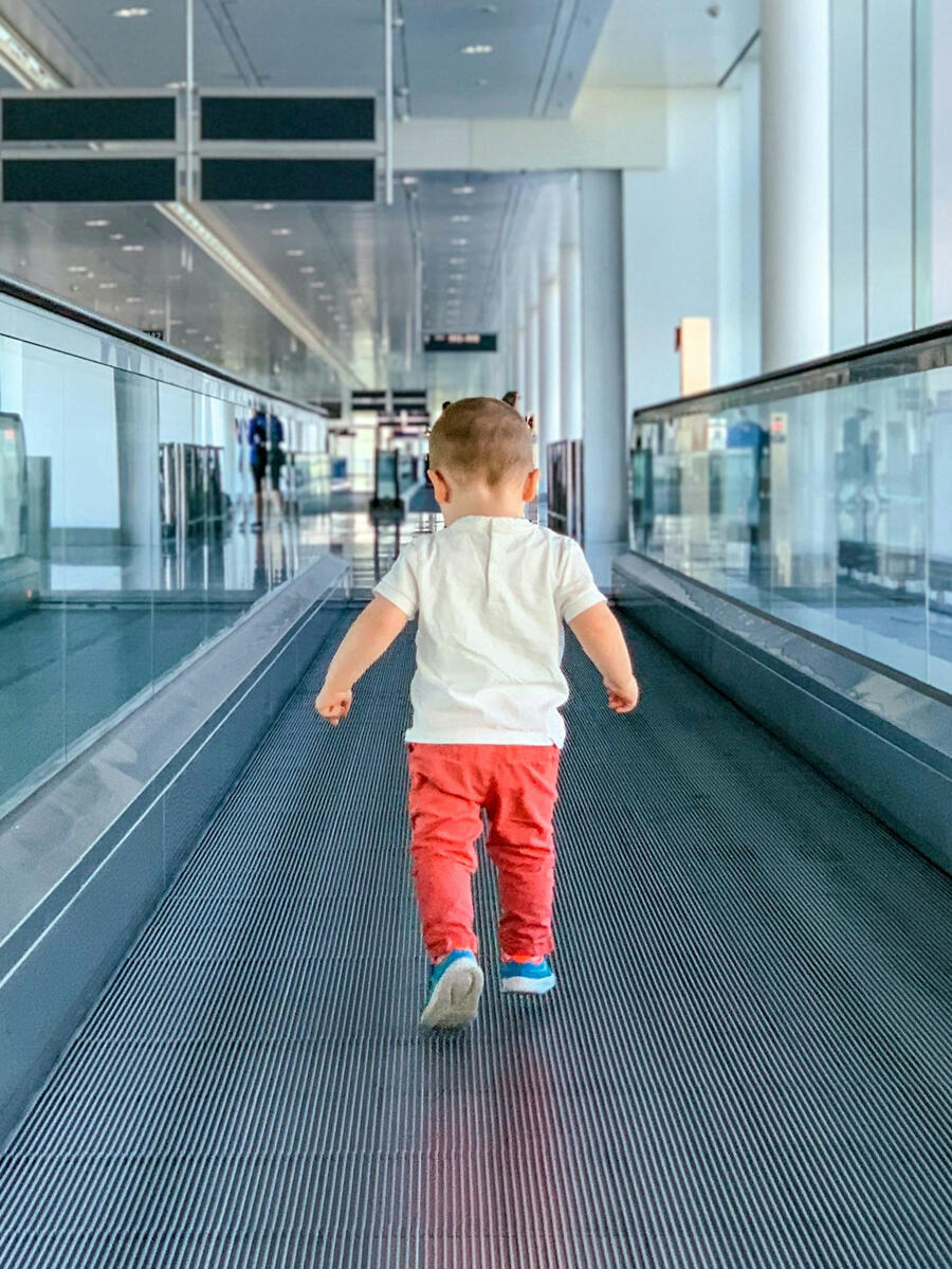 Exploring new adventures — Vacay Fuel family journey Young boy walking on an escalator in an airport, viewed from behind