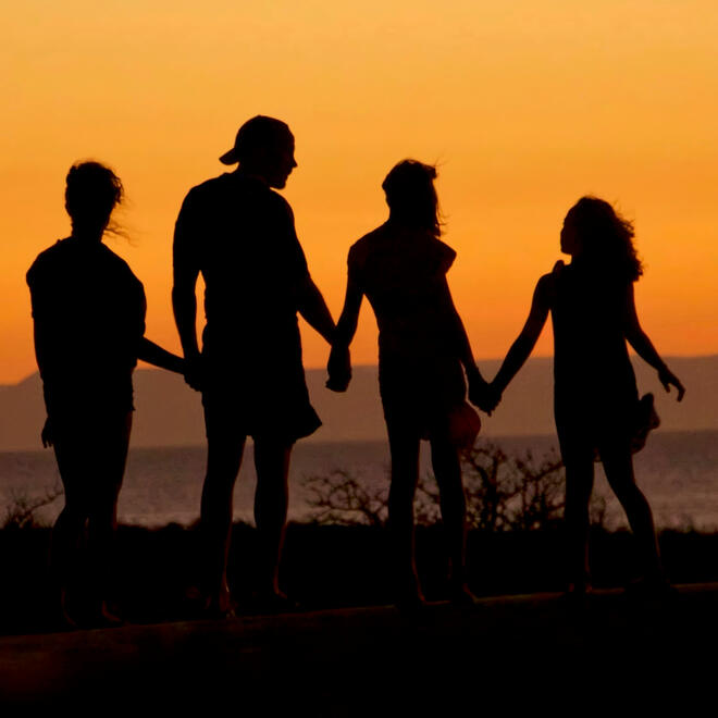 Family togetherness at sunset — Vacay Fuel Silhouette of a family holding hands under a sunset, symbolizing togetherness and adventure
